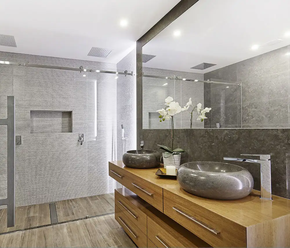 Ein Badezimmer mit einem großem Glasspiegel und einer Dusche mit Glaswänden